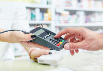 Shopping at the pharmacy with a credit card and entering a security pin on the terminal, hands close up