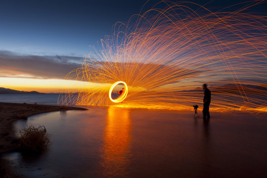 Photographer in lake shooting picture of spinning sparks at sunset. Pyramid Lake, NV.