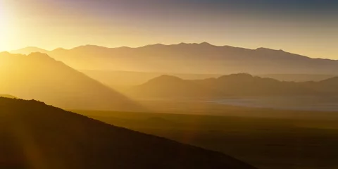 Fotobehang Woestijnlandschap zonsondergang met zonnevlam en nevel © neillockhart