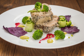 Pork medallions in cream sauce and micro greens on a white plate. Wooden background. Top view. Close-up
