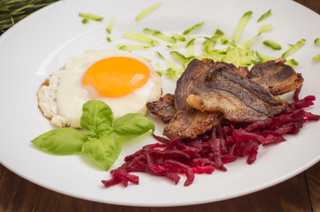 English breakfast in the Christmas of eggs, fried bacon and salad  grated boiled beet  cucumber. Wooden background. Top view