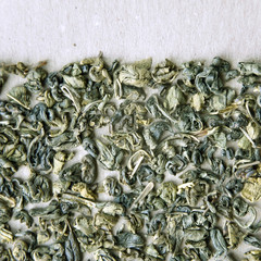 Big leaf green tea on a cardboard surface.