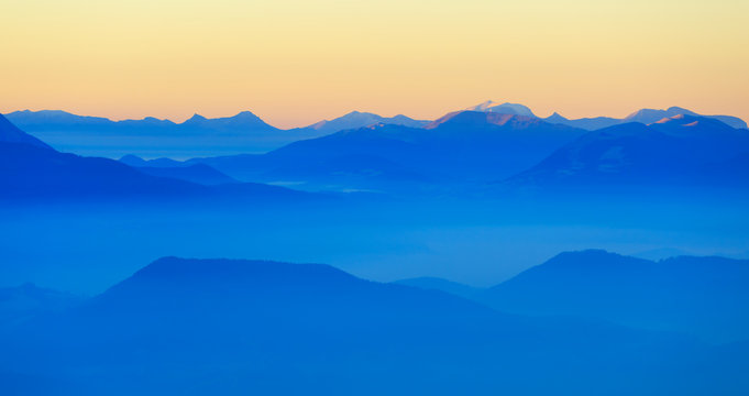 Colorful dusk in the French mountains, with the valley filled with fog.