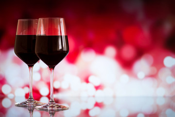Two glasses of red wine against bokeh background with sparkles and roses. Very shallow depth of field. Selective focus, copy space
