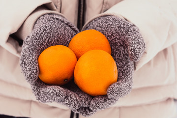 Hands in knitted gloves holding tangerines