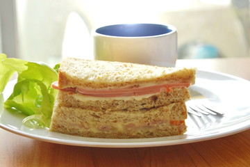 pork bologna whole wheat sandwich with fresh green oak and coffee on dish