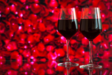 Two glasses of red wine against bokeh background with sparkles and roses. Very shallow depth of field. Selective focus, copy space