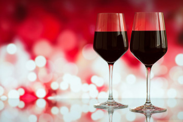 Two glasses of red wine against bokeh background with sparkles and roses. Very shallow depth of field. Selective focus, copy space