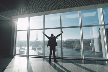 Business man celebrate victory and success in work alone against panoramic windows