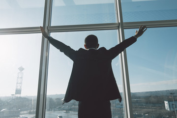 Business man celebrate victory and success in work alone against panoramic windows