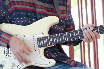 .Young Living and practicing electric guitar happily at home. © Tongra