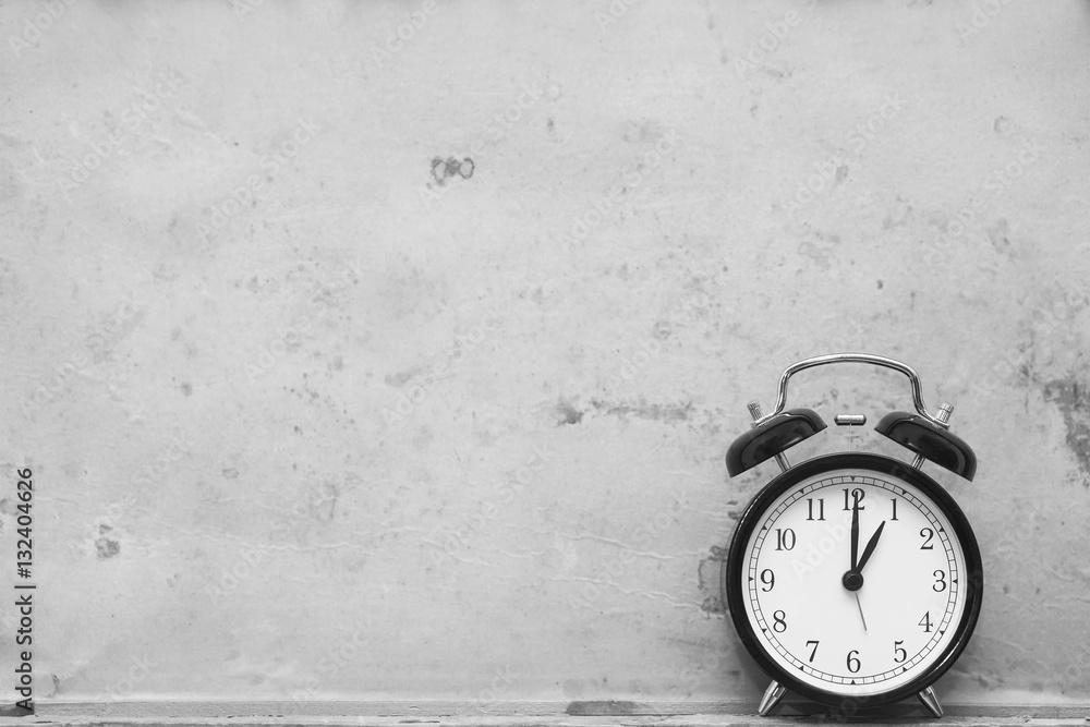 Wall mural alarm clock showing one o'clock on wooden background. black and white