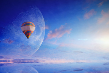 Hot air balloon in blue sky with rising full moon