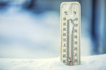 Thermometer on snow shows low temperatures under zero. Low temperatures in degrees Celsius and...