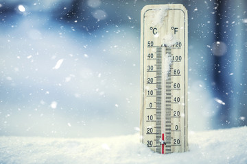 Naklejka premium Termometr na śniegu pokazuje niskie temperatury poniżej zera. Niskie temperatury w stopniach Celsjusza i Fahrenheita. Zimna zima pogoda dwadzieścia poniżej zera.