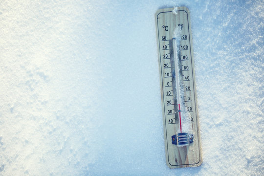 Thermometer on snow shows low temperatures under zero. Low temperatures in degrees Celsius and fahrenheit. Cold winter weather twenty under zero.
