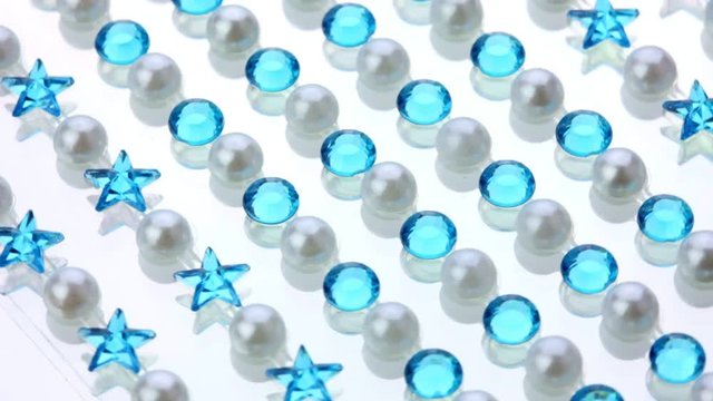 colored shiny pearl and blue rhinestones on mirror surface spinning background