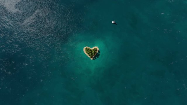 Island in the form of heart in the ocean and flying plane zoom in. 3D rendering animation.