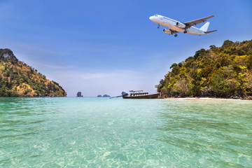 passenger airplane flying above small island in tropical andaman sea with sunlight. travel destinations concept