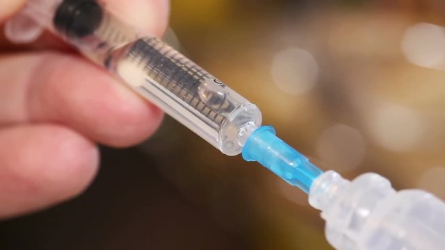 Syringe taking a liquid  medicament from capsule.
