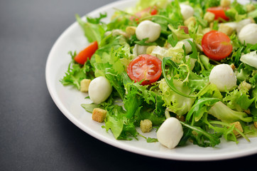 Fresh salad on a white plate on a black table