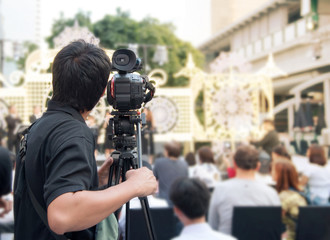 Back of young cameraman using a professional camcorder outdoor  filming music show or mini concert...