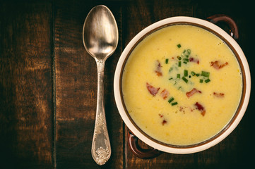 Corn cream soup with bacon (chowder) on wooden background.