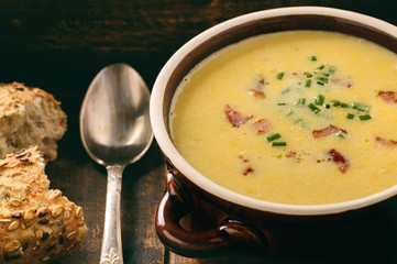 Corn cream soup with bacon (chowder) on wooden background.