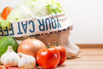 Fresh vegetables in weave bag holding, on wood on white background.