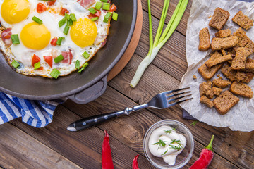 Fred eggs in pan with tomatoes and green fresh onion.