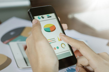 Business concept. Woman's hands using smart phone with financial