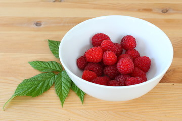 red raspberry fruits in a small white bowl