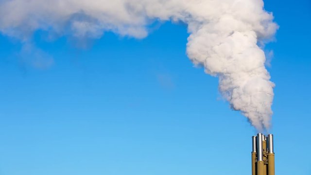 White smoke rising from smokestacks into the blue sky. Conceptual video of toxins like carbon, carbon dioxide and other polluting gases released into the atmosphere.