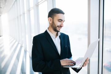 Handsome businessman in suit with laptop in flight terminal