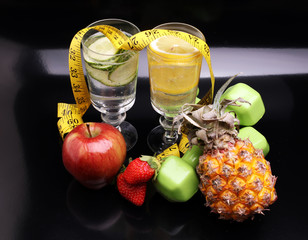 fitness equipment and healthy food and detox water (green apple, pepper, grapes, nectarines, kiwi, orange, dumbbells and measuring tape) 