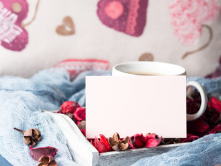 Obraz na płótnie Canvas Blank paper note for Valentine's or mother day and coffee mug. Pillow with hearts and flower petals