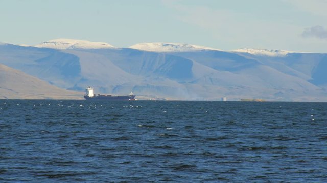 trawler in Atlantic ocean near coast of Reykjavik, snow on the top of mountain
