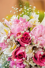 Obraz na płótnie Canvas Wedding rings at a flower bouquet