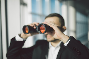 american businessman using binoculars in office