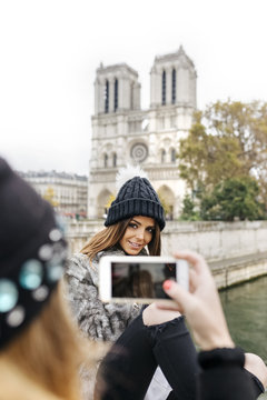 France, Paris, tourist taking picture of her friend in front of Notre Dame