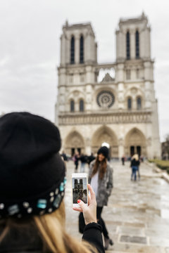 France, Paris, tourist taking picture of her friend in front of Notre Dame