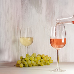 Rose wine poured into glass, with grapes in background