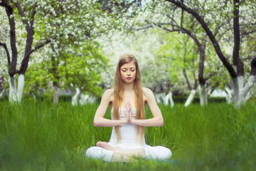 beautiful woman is doing yoga in the blossoming garden