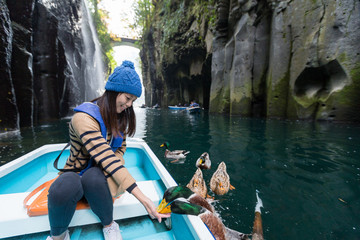 Woman feeding duck and sitting on boat