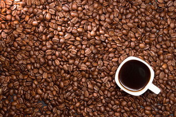 Coffee background. Coffee beans and cup of coffee over table.