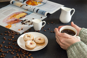 Cup of coffee in woman hands. Saucer with cookies, roasted coffe