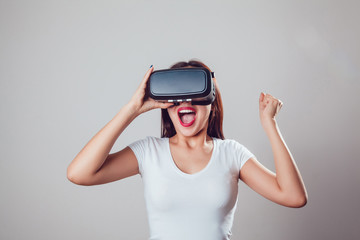 Attractive and happy woman using virtual reality goggles on grey background. VR headset.