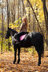 girl walking in the autumn forest on horseback