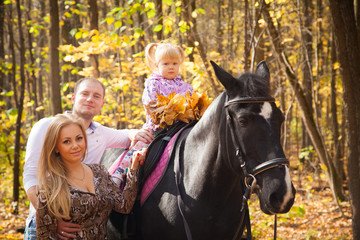 Fototapeta premium young family walking in the autumn forest with a horse
