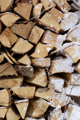 Chopped firewood logs in a pile with snow